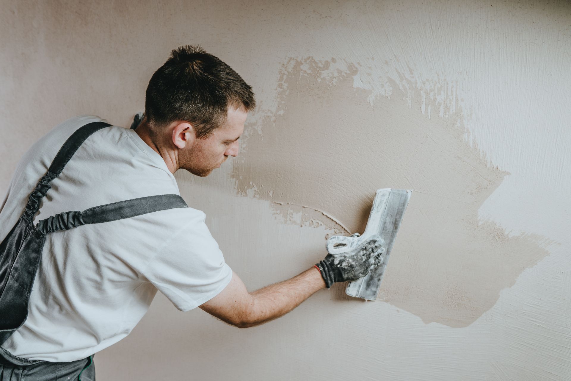 Painter applying white plaster to a wall with a trowel
