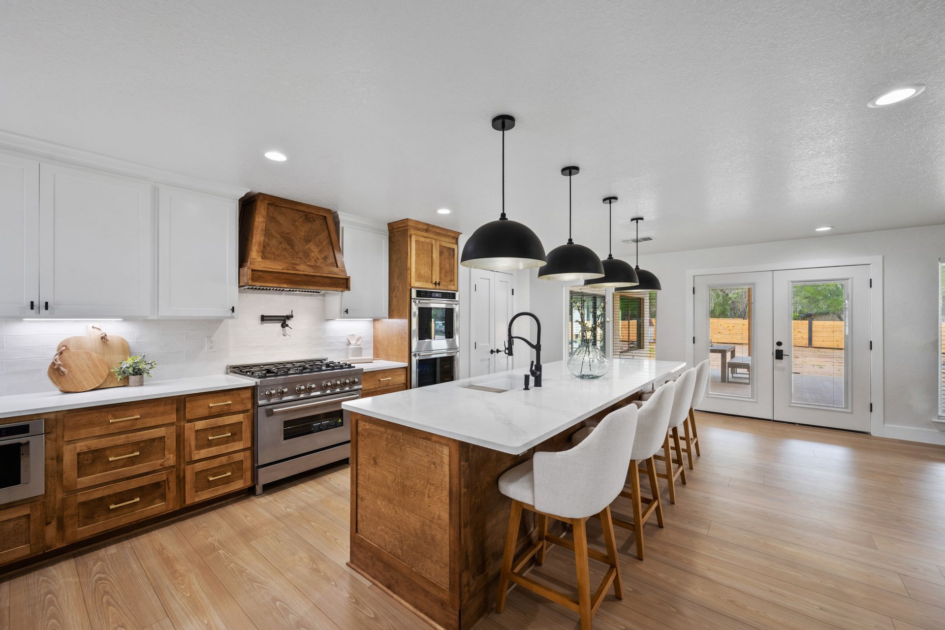 Bright modern kitchen with white cabinets, wood island, bar stools, and stainless steel appliances