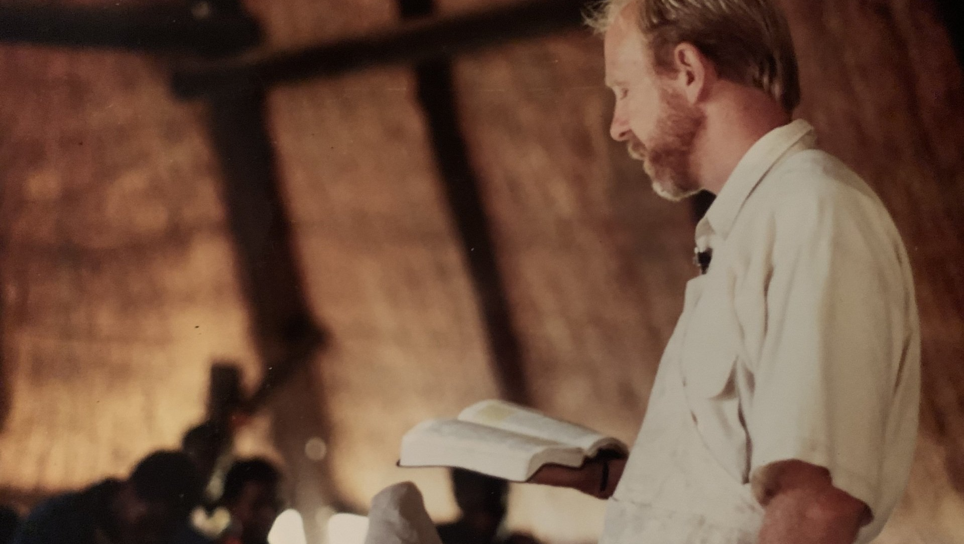 A man in a white shirt is reading a bible