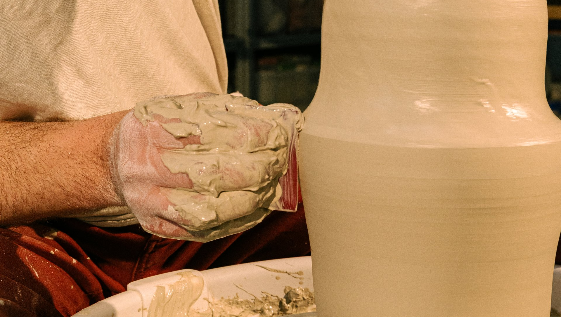 A person is making a vase on a pottery wheel