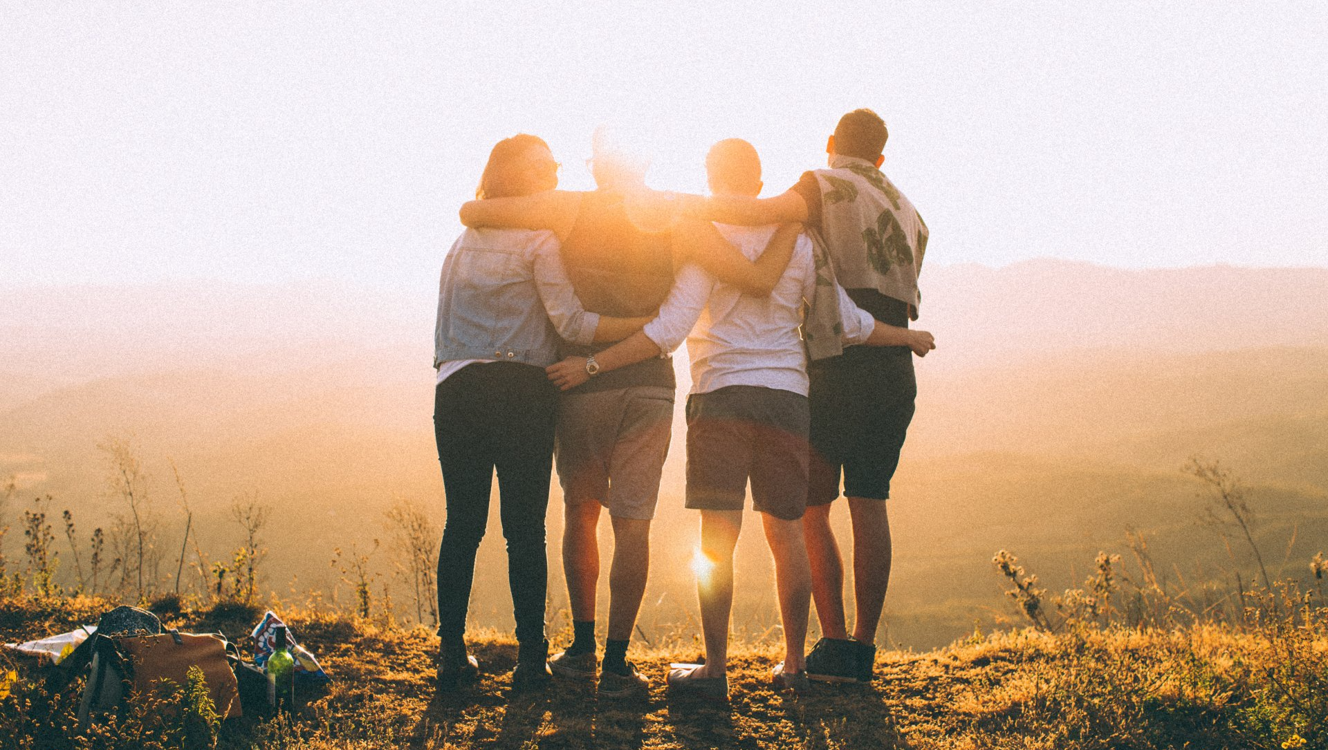 A group of people are hugging each other on top of a hill.