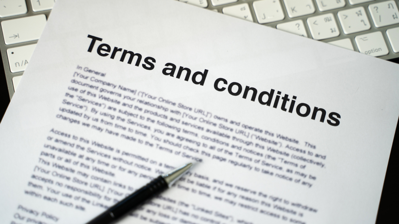 Terms and conditions document with a pen on top, sitting in front of a keyboard.