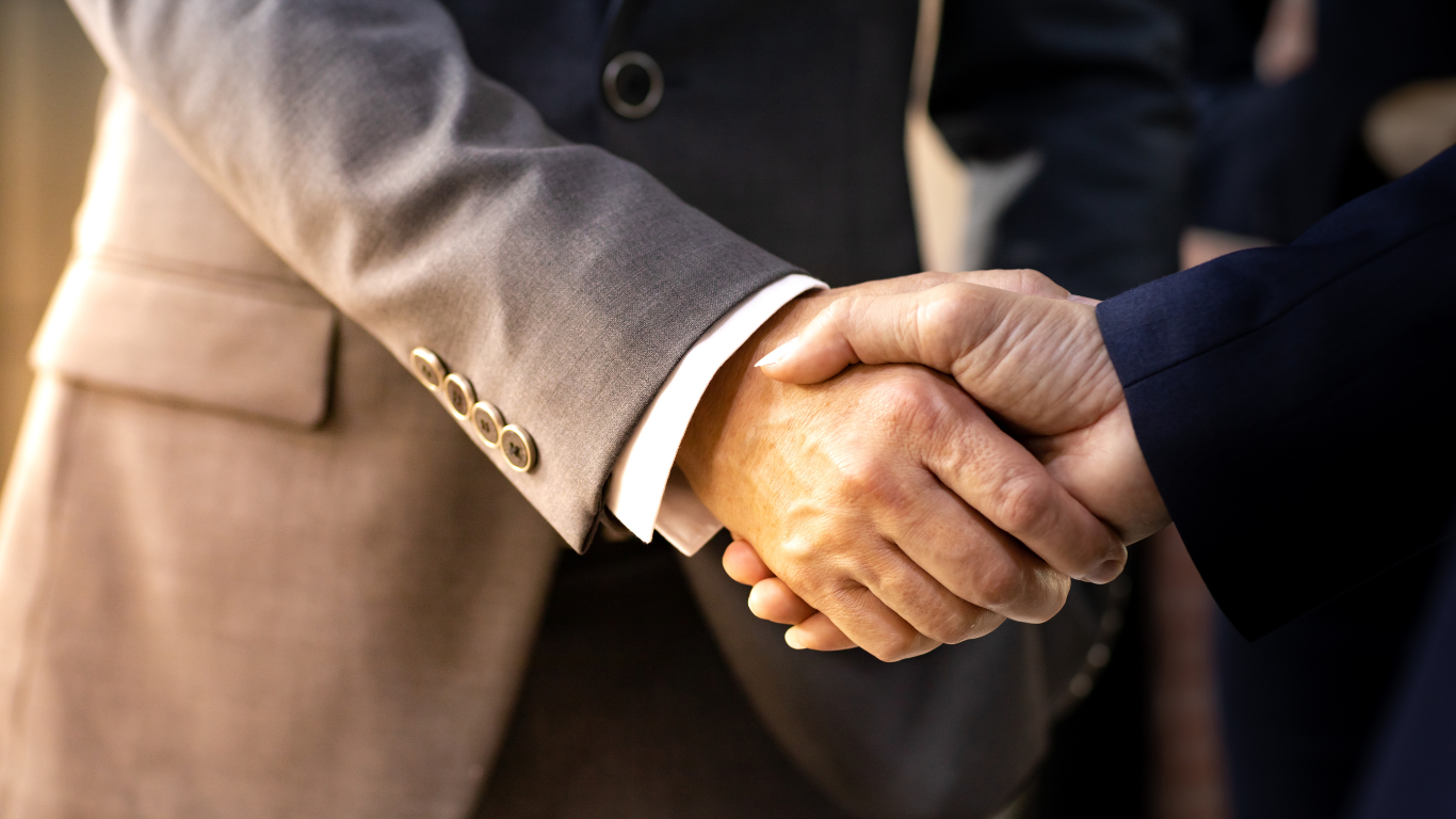 Two people in suits shaking hands.