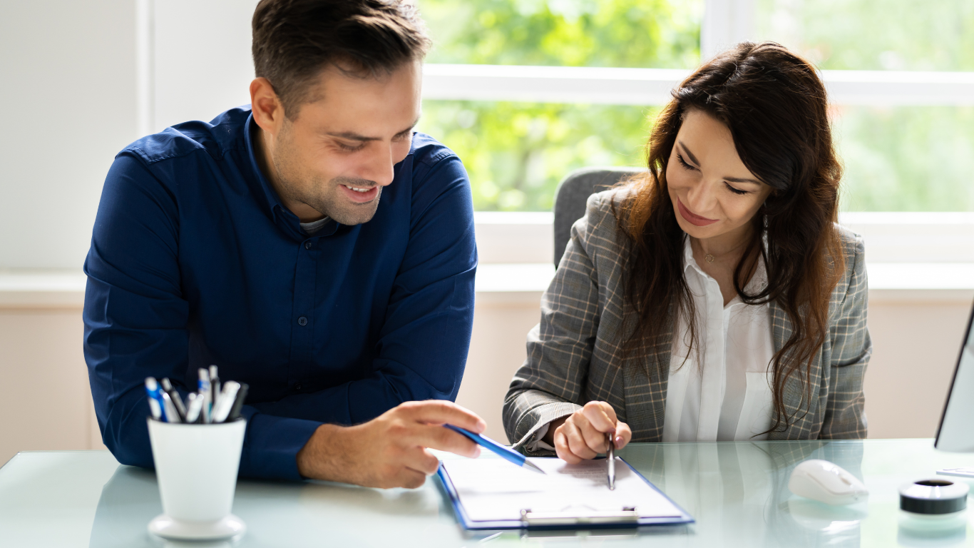 Two people reviewing documents at a desk, smiling.