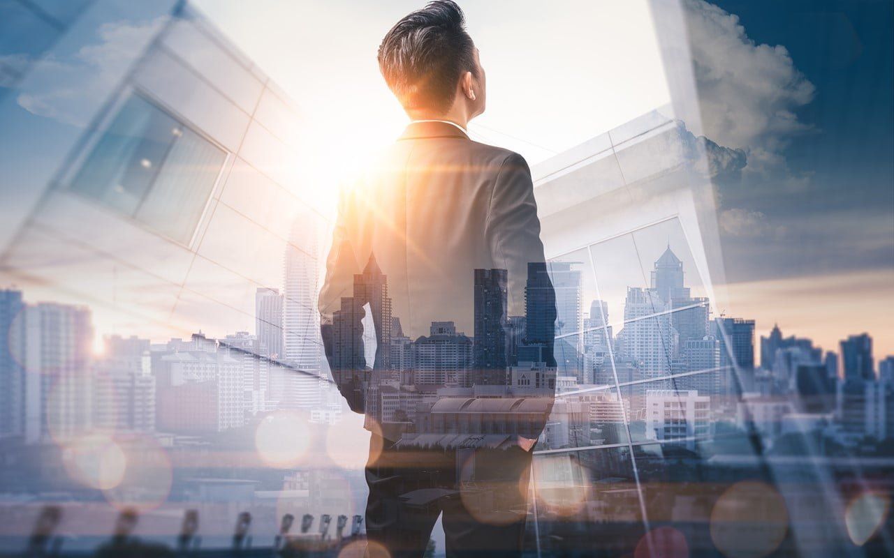 Businessman overlooking city skyline, sunlight, double exposure, looking upward.