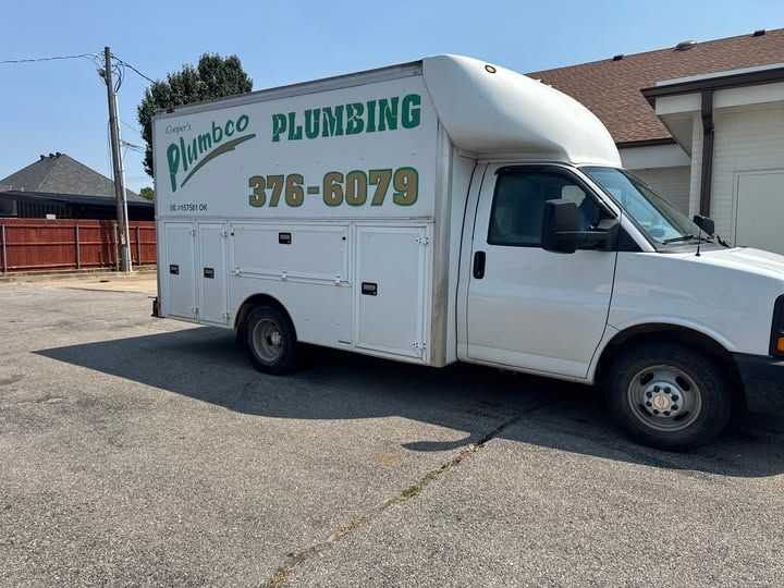 White plumbing service truck with the company name and phone number on the side, parked outside.