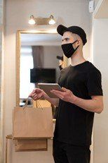 a man holding a brown paper bag and an iPad