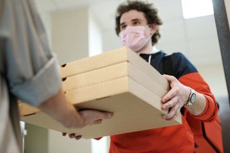 Man wearing mask receiving pizza delivery