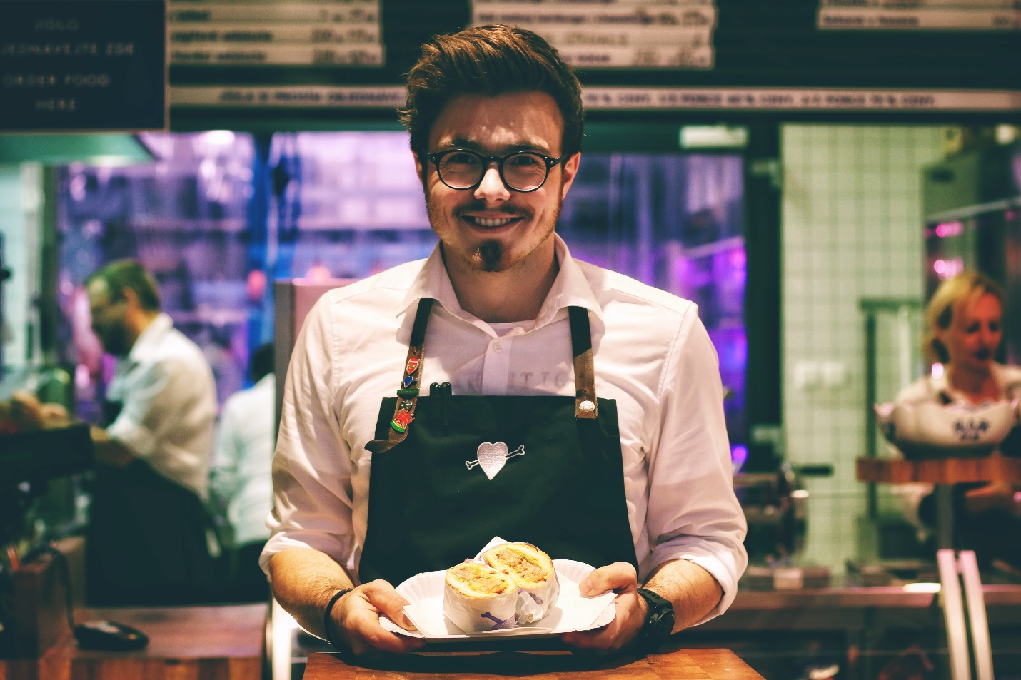 : A smiling waiter, holding a plate full of food.
