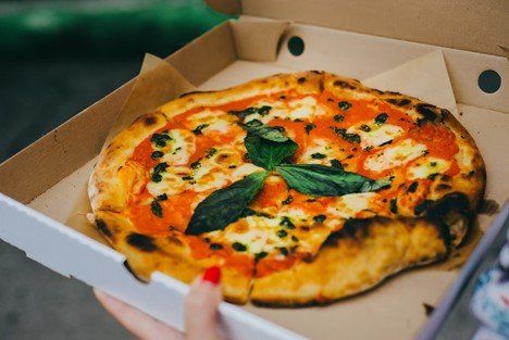 A woman holding her takeout pizza