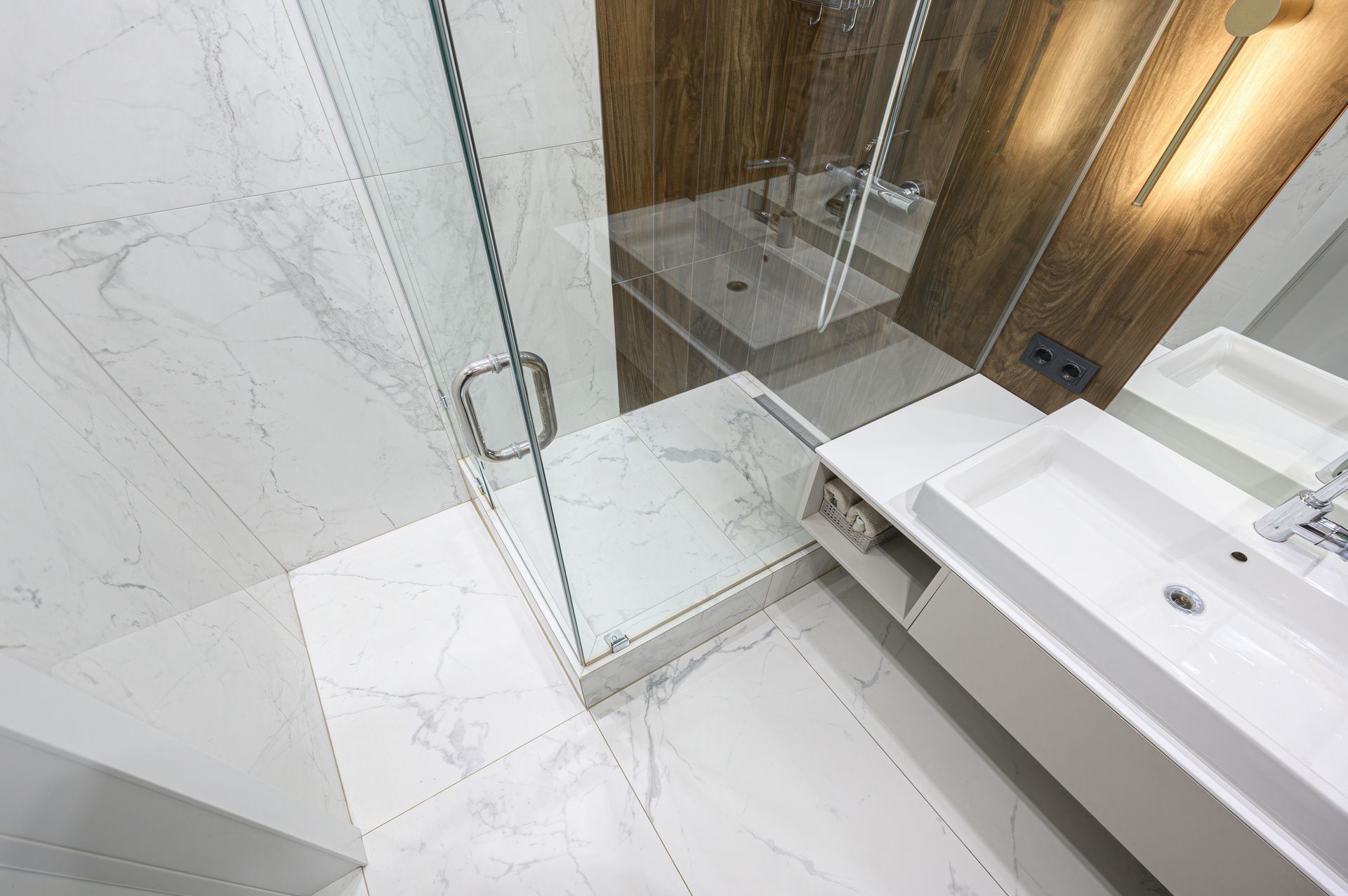 Modern bathroom with glass shower, white marble tiles, and a sink vanity