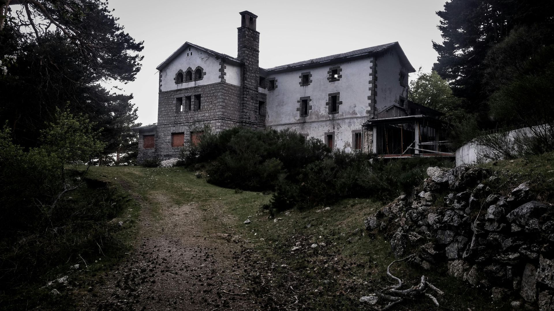 Une photo en noir et blanc d'une maison abandonnée entourée d'arbres.