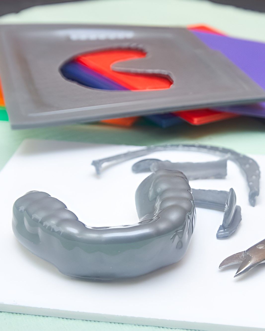 A Mouth Guard is Sitting on a Table Next to a Pair of Scissors — Yeppoon Denture Clinic in Taranganba, QLD