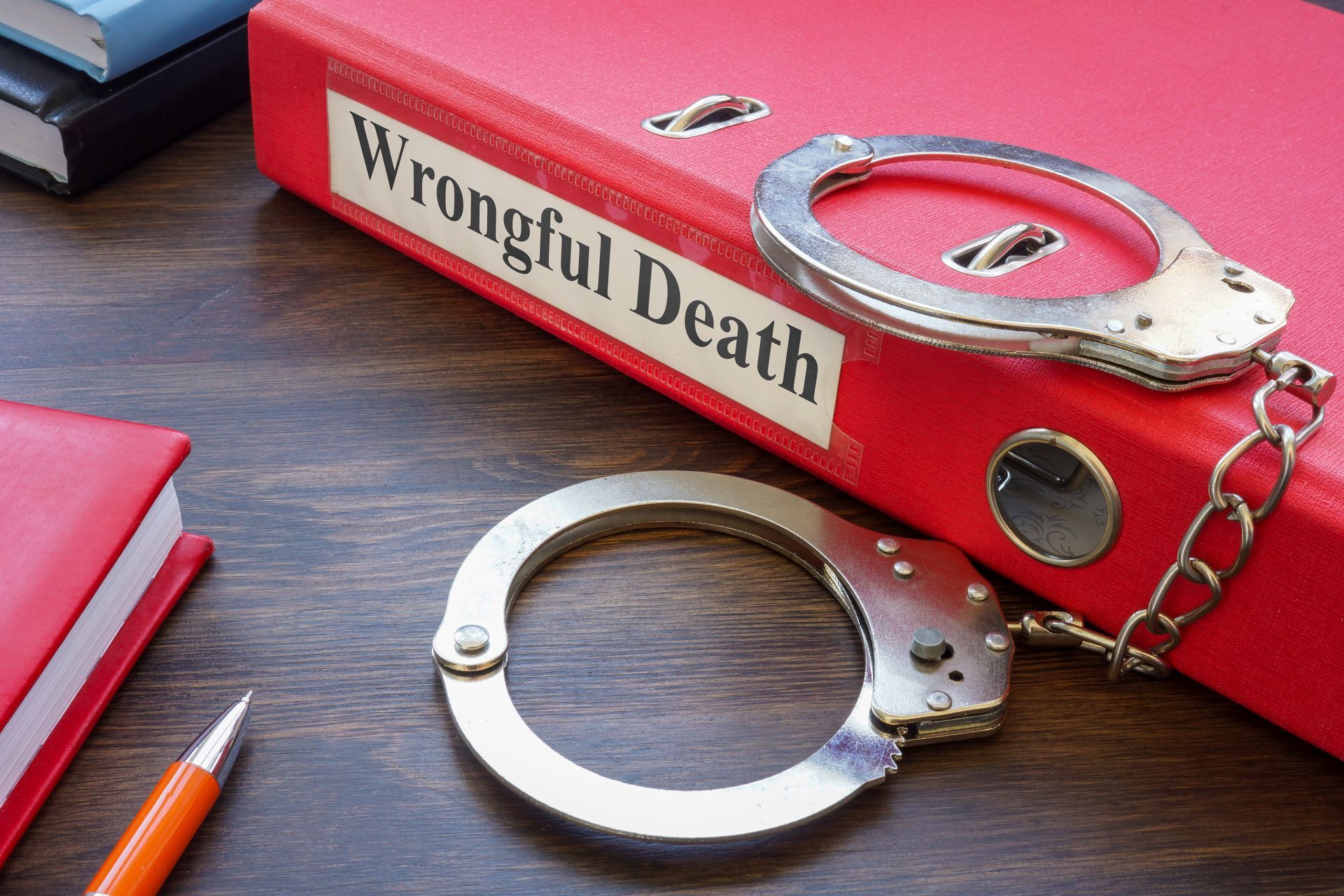 Handcuffs on a red folder labeled “Wrongful Death” beside a pencil on a desk Handcuffs on a red folder labeled “Wrongful Death” beside a pencil on a desk