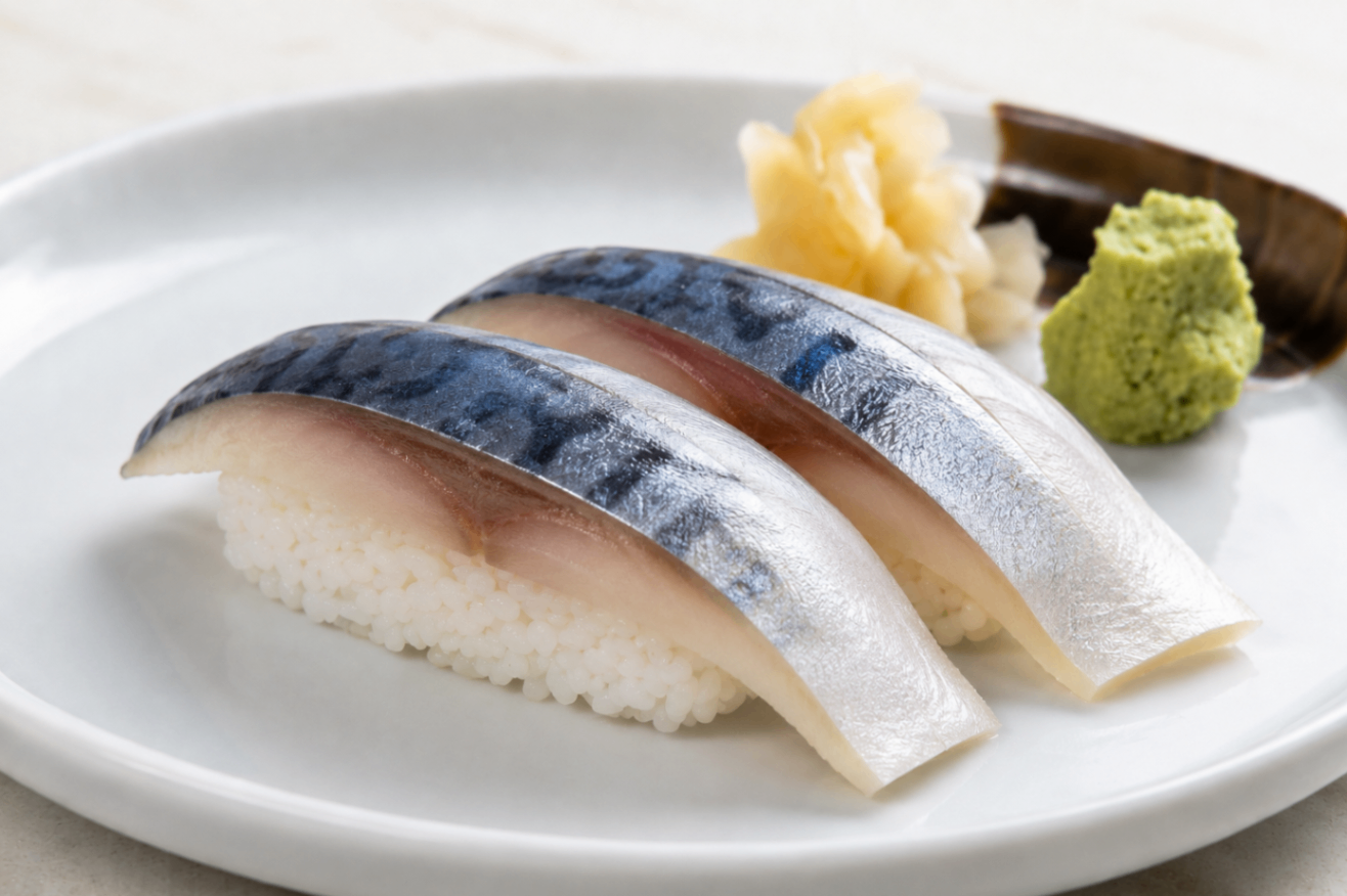 Three pieces of mackerel sushi on a white plate with pickled ginger and wasabi