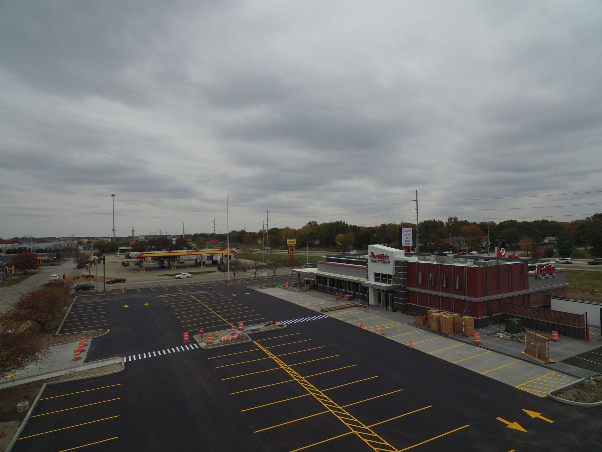 An aerial view of a gas station and newly paved parking lot under a cloudy sky.