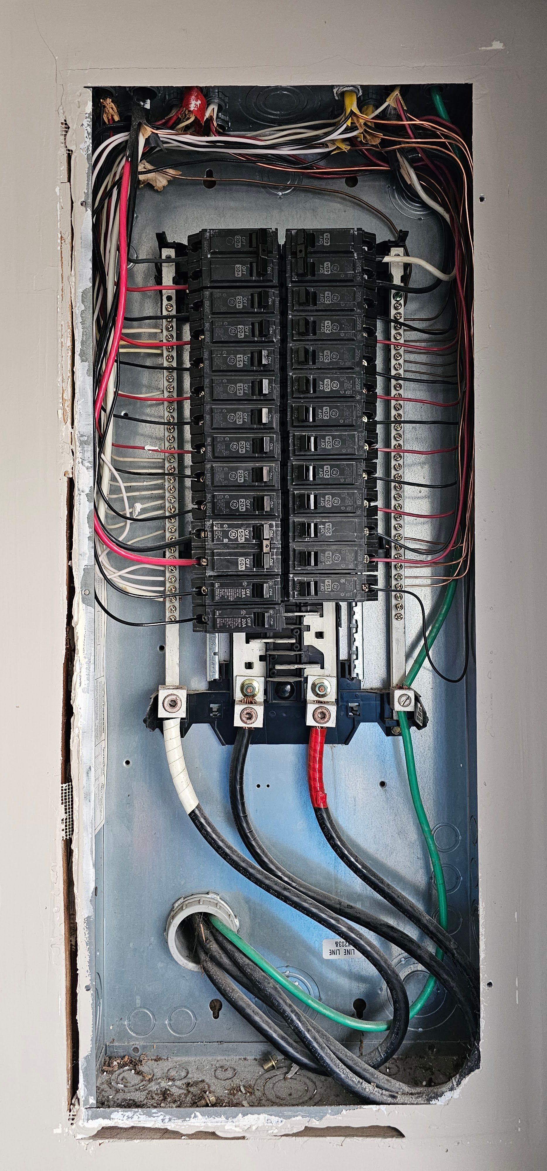 Open electrical breaker panel with exposed wiring and multiple circuit breakers in a metal box.