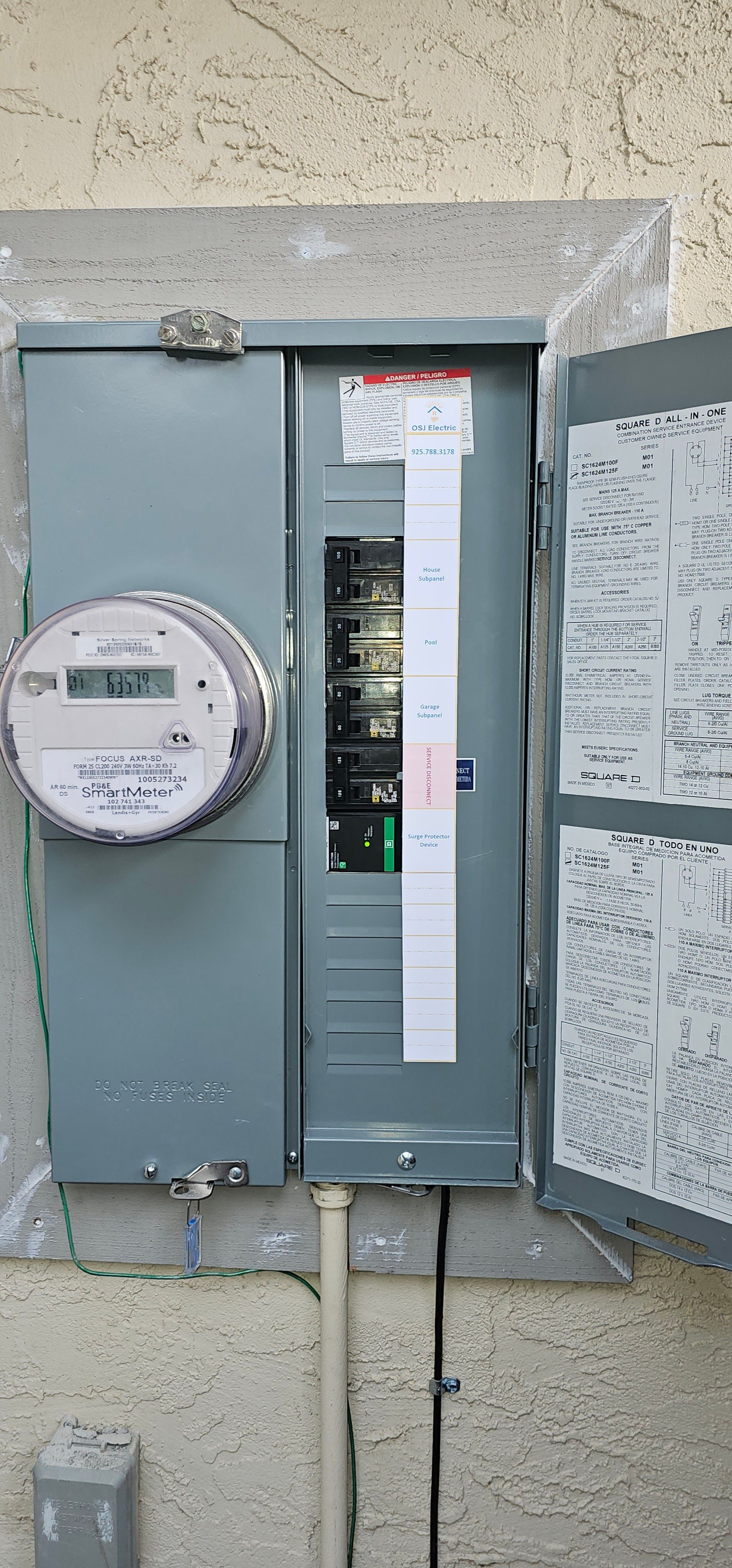 Open electrical breaker panel with meter on a stucco wall