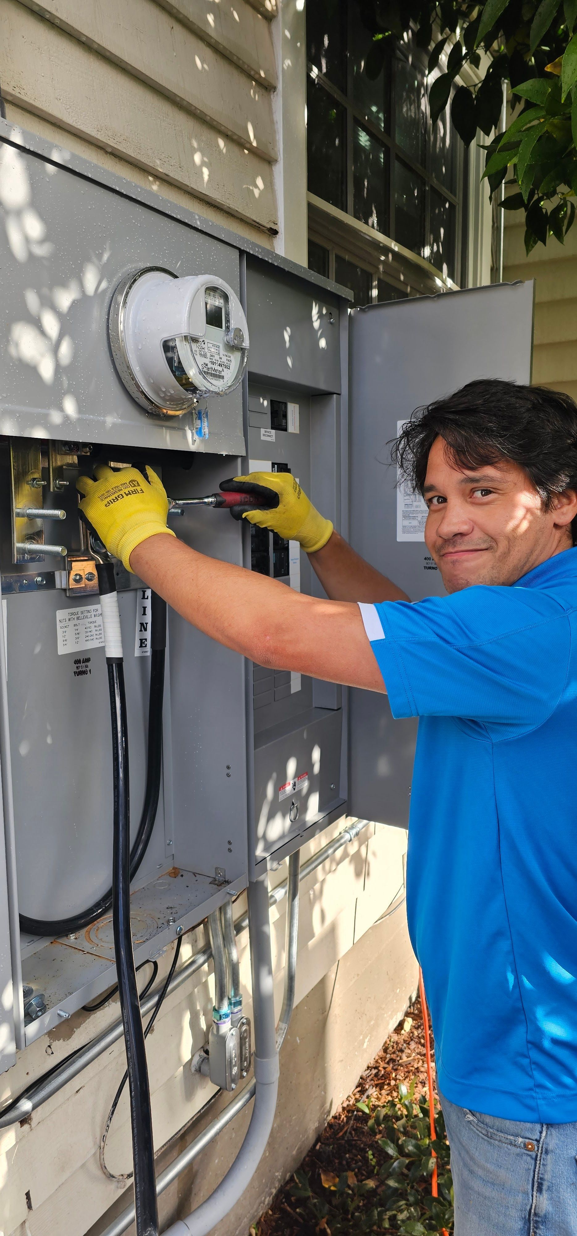 Technician in blue shirt adjusting electrical equipment on an outdoor wall