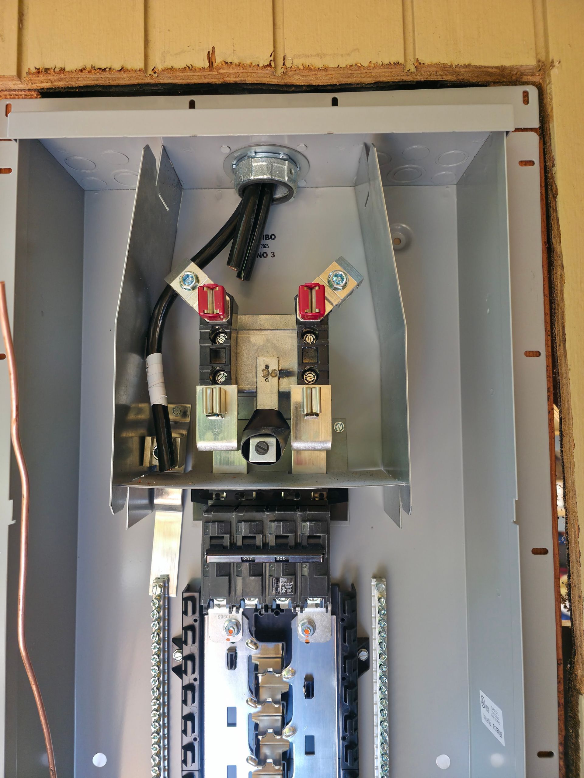 Open electrical breaker panel with wires and switches inside a gray metal box.