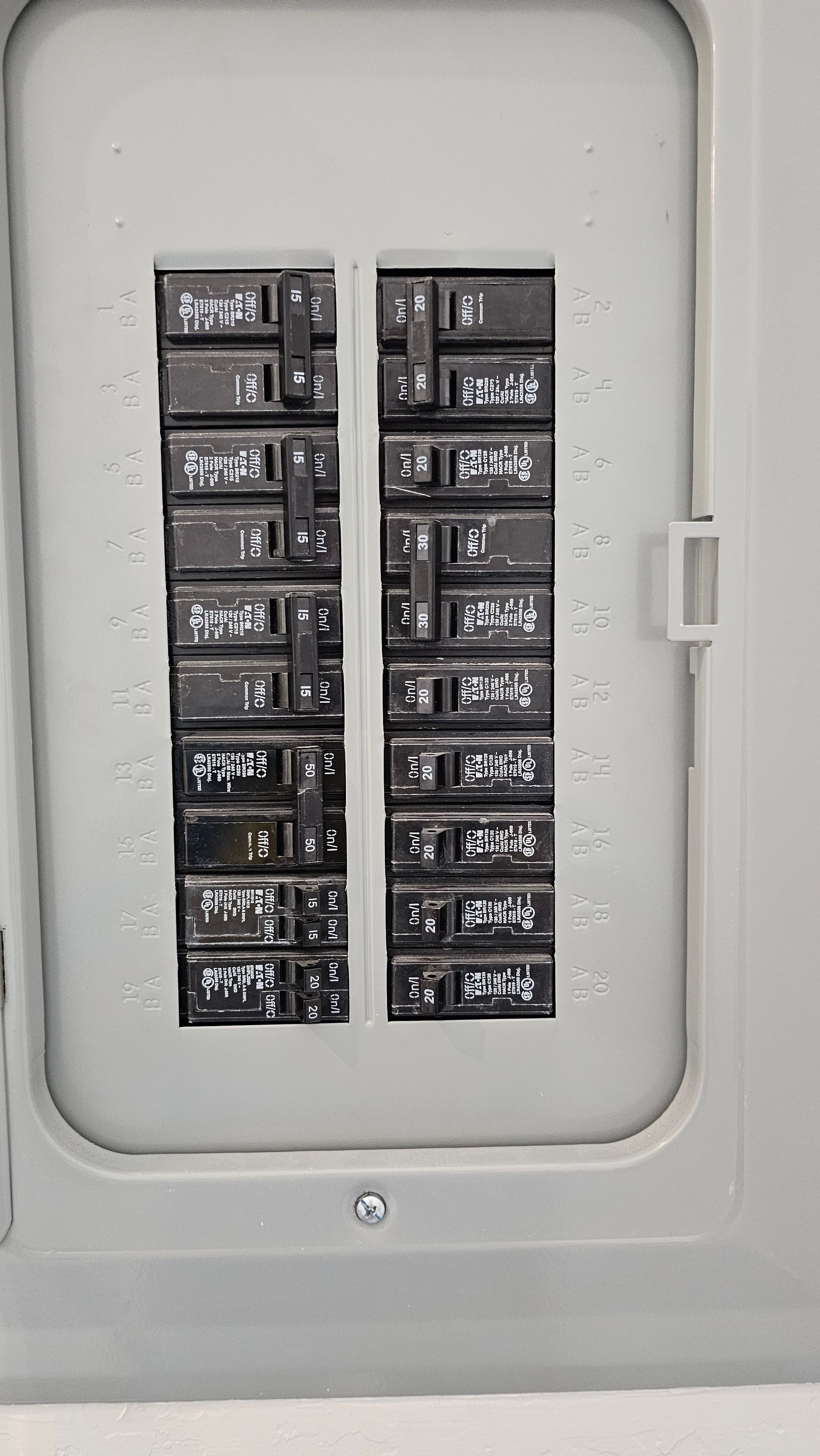Electrical breaker panel with two columns of black circuit switches in a gray metal box