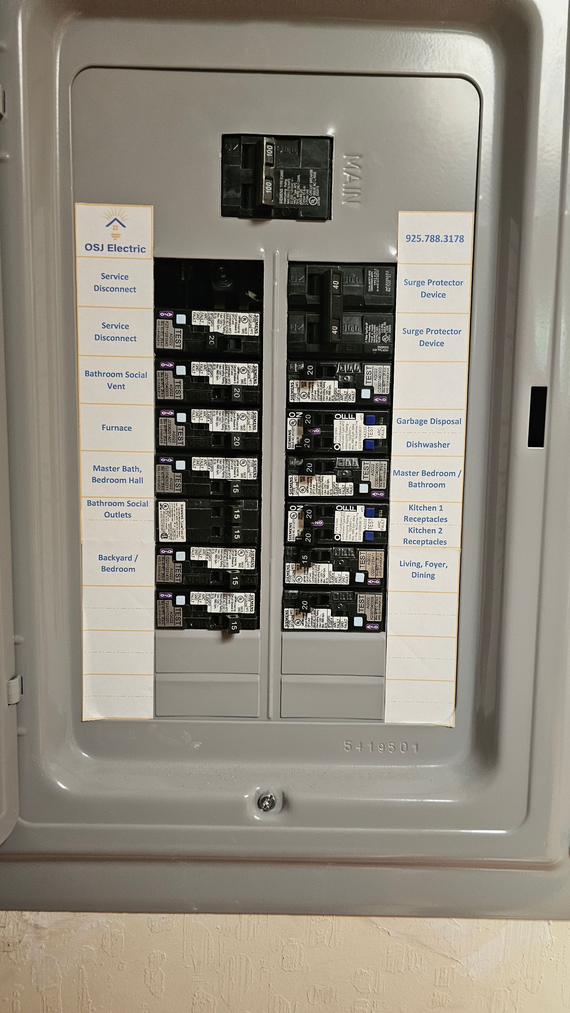 Electrical breaker panel with rows of black switches in a gray metal box, labels on both sides.