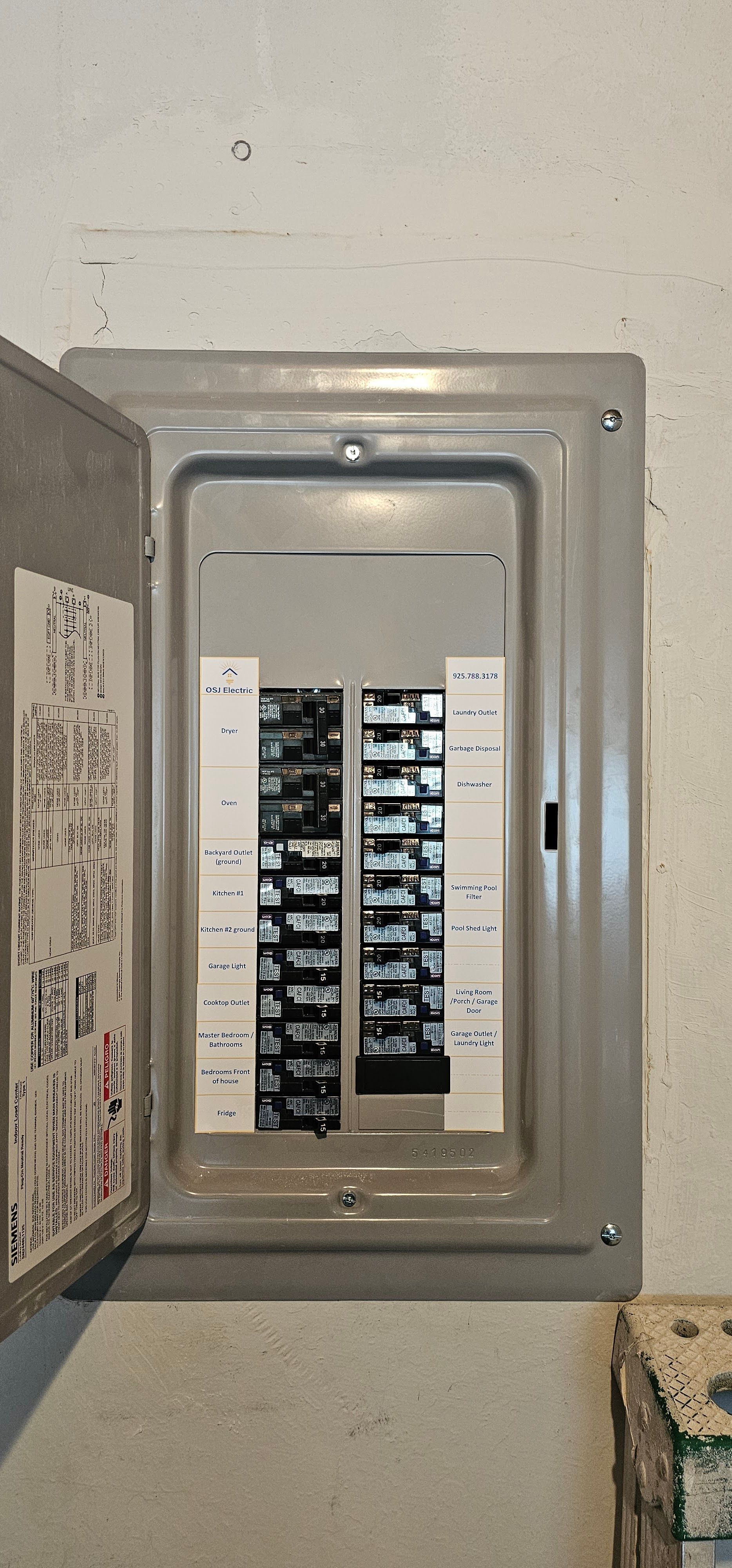 Open electrical breaker panel on a wall with rows of switches visible inside