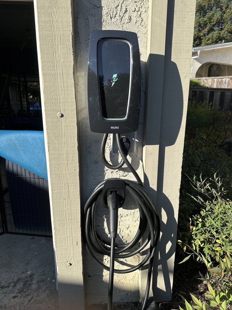 Outdoor EV charging station mounted on a post, with a coiled cable in sunlight
