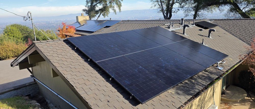 Rooftop solar panels on a house with a view of water and hills in the background