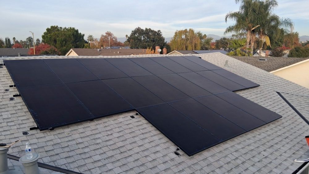 Solar panels installed on a shingled roof under a clear sky.