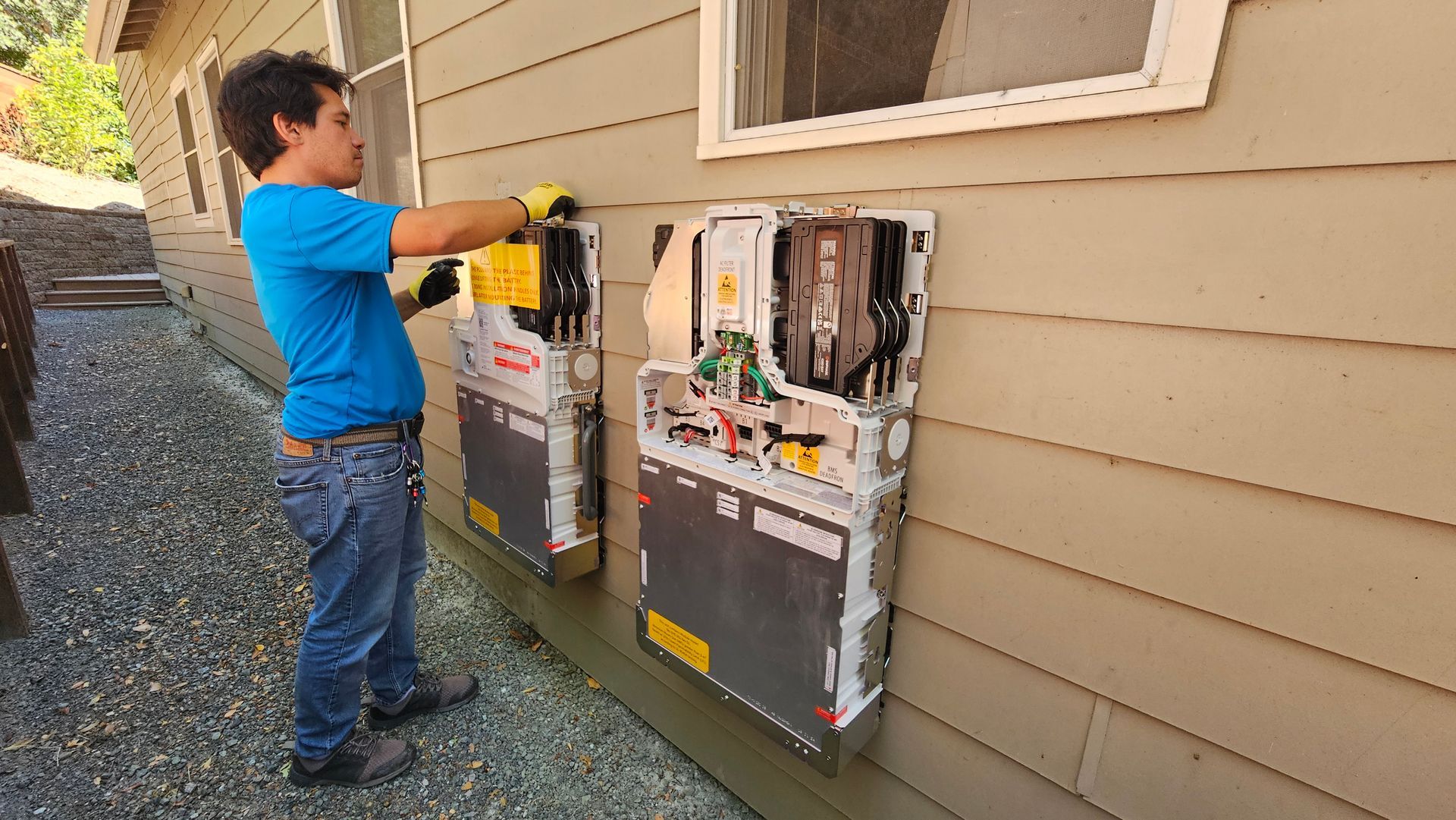 Technician working on outdoor utility meters mounted on a house wall