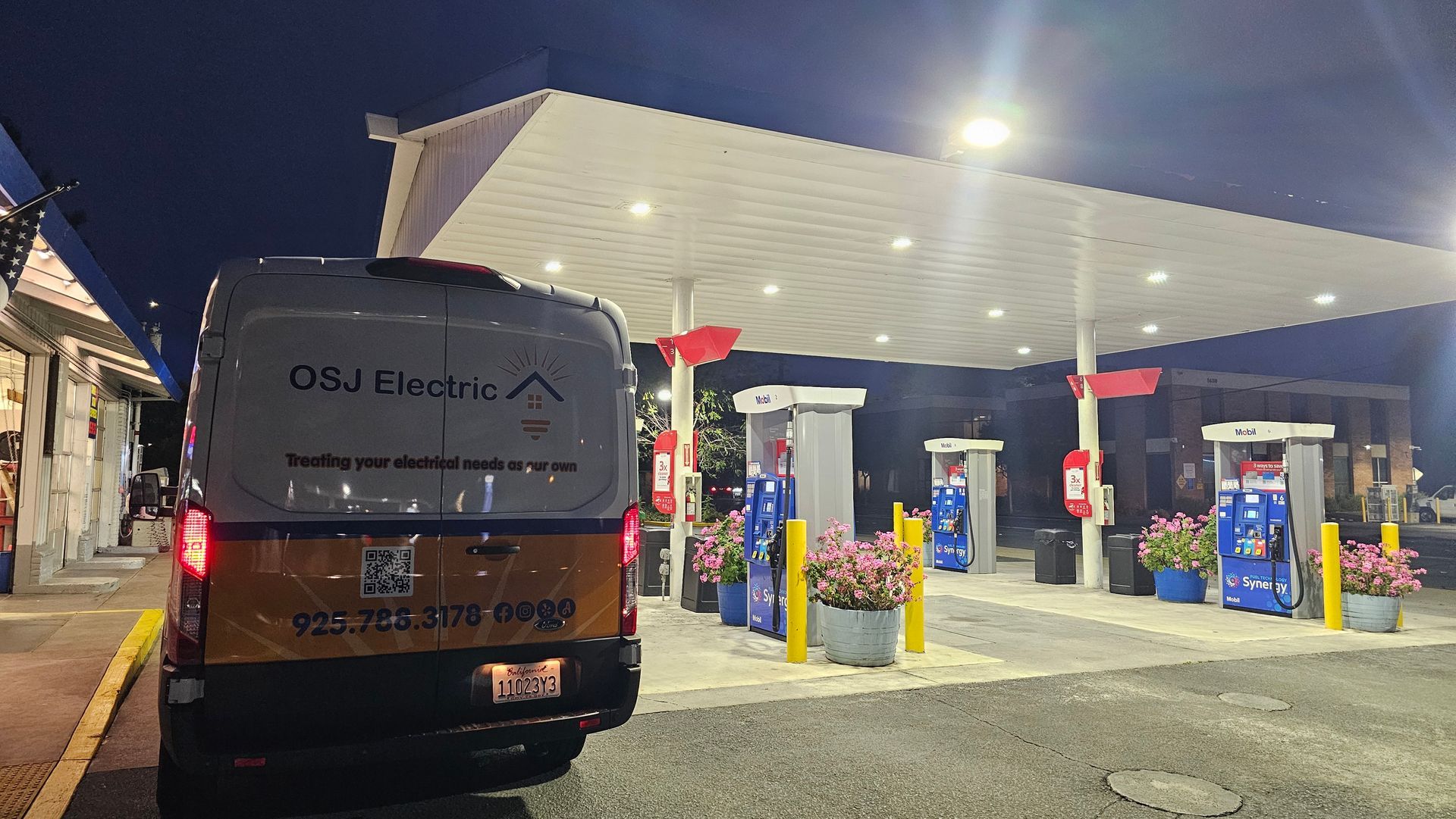 Gas station at night with a van parked at the pumps under a bright canopy.