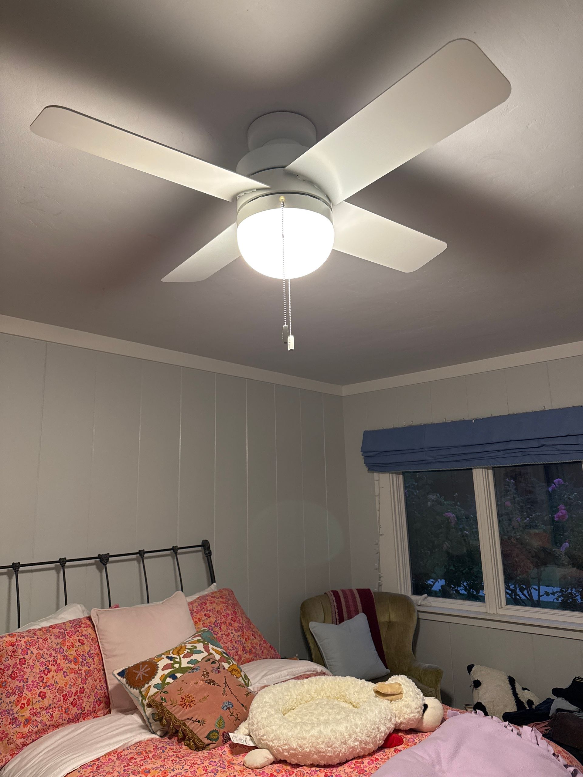 Bedroom with a bed, pillows, ceiling fan, and a window with blue valance.