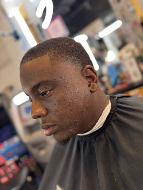 A man is getting his hair cut at a barber shop.