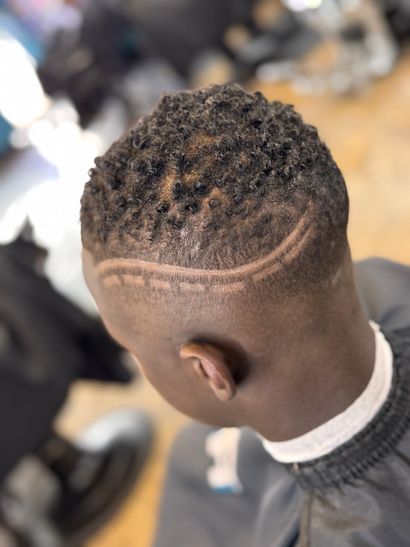 A man with dreadlocks is getting his hair cut by a barber