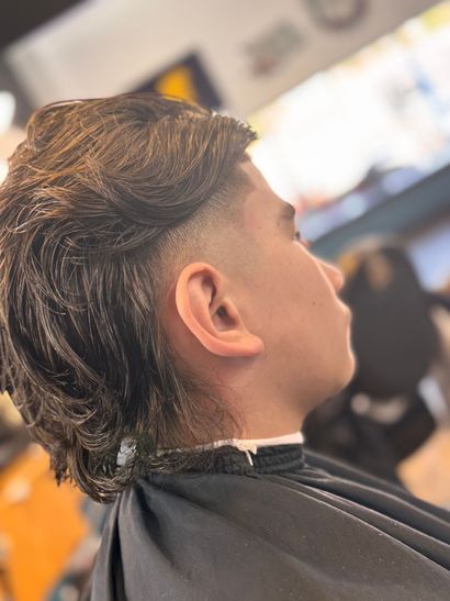 A young man is getting his hair cut at a barber shop