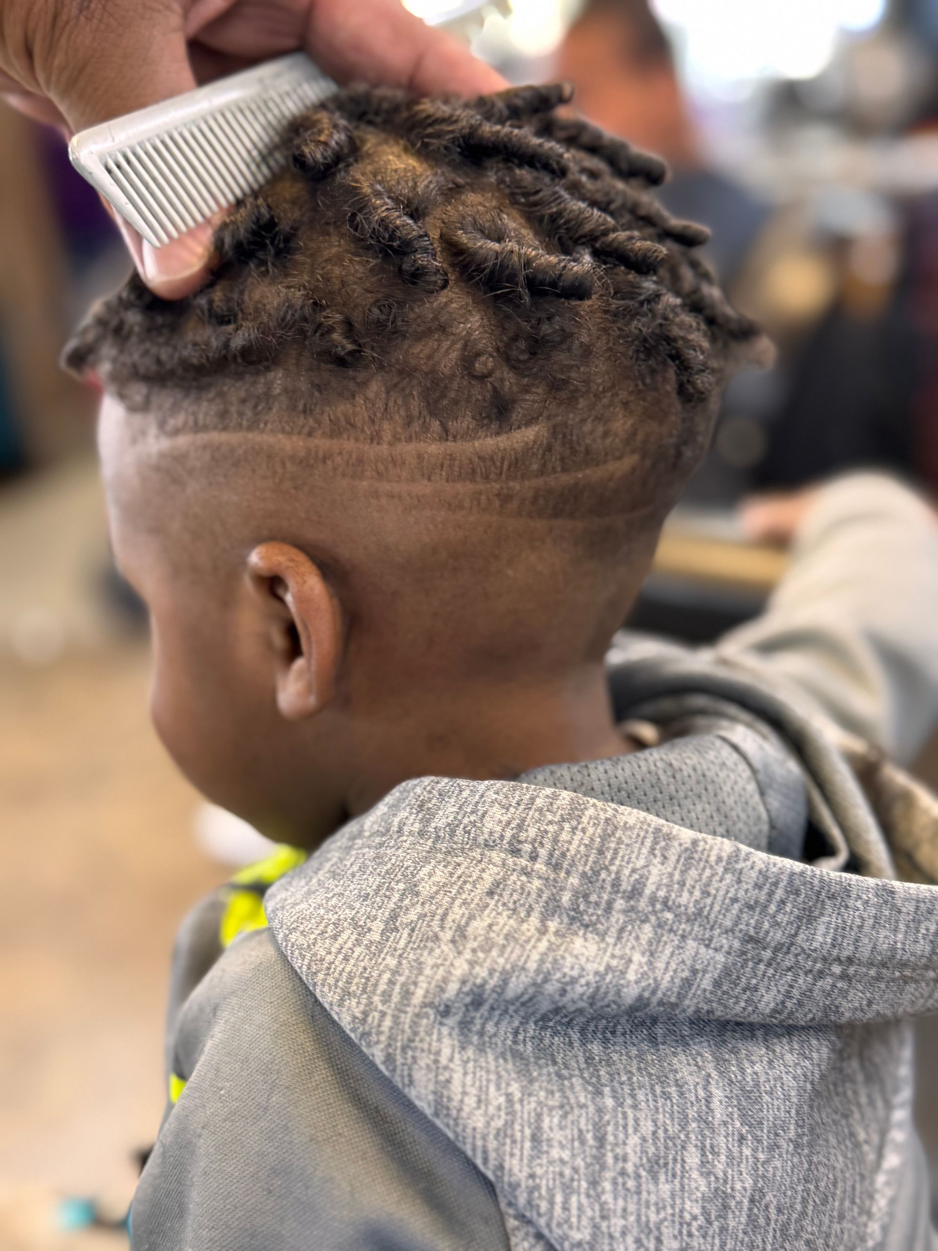 A young boy is getting his hair cut at a barber shop.