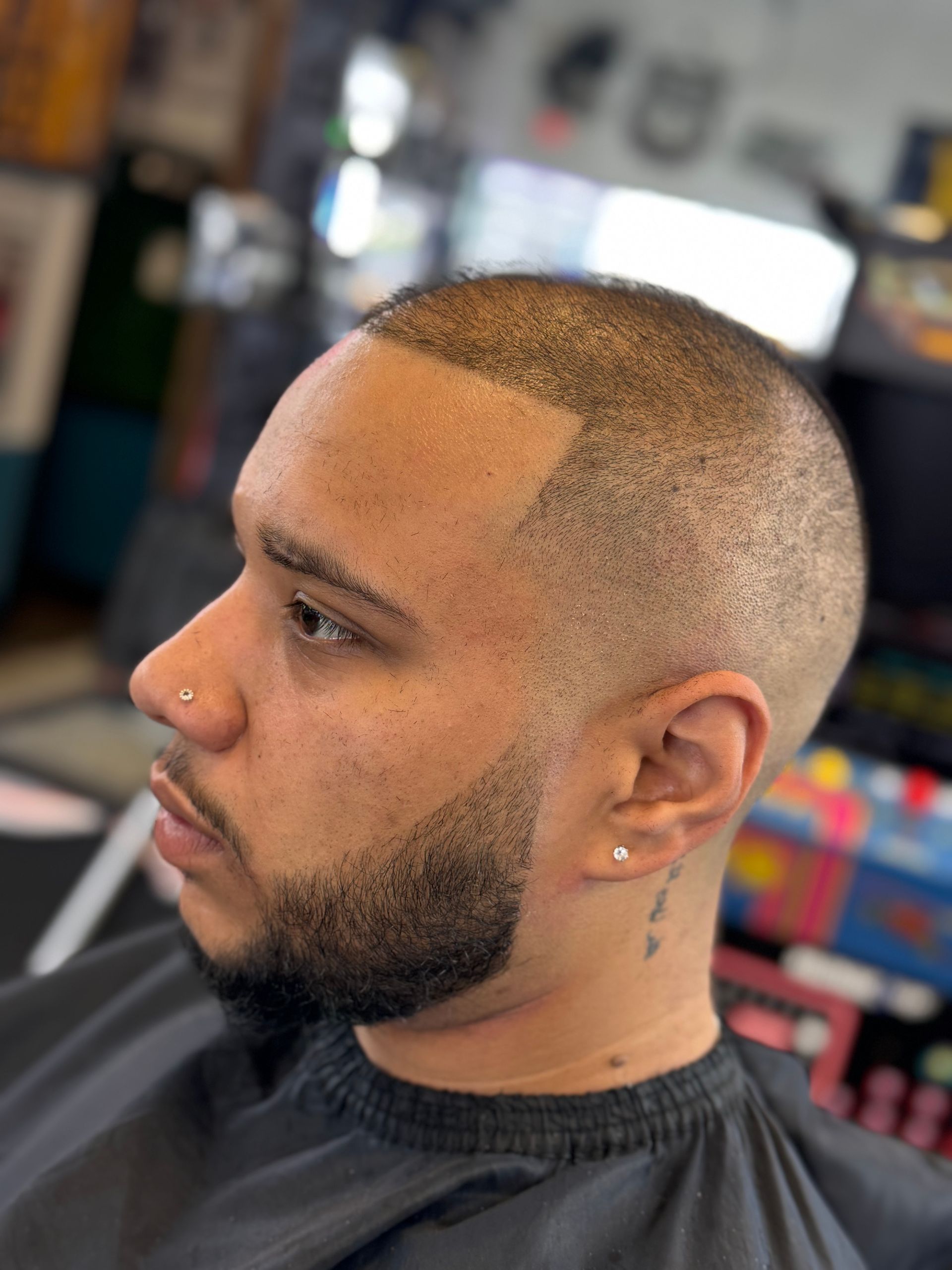 A man with a beard is getting his hair cut at a barber shop.