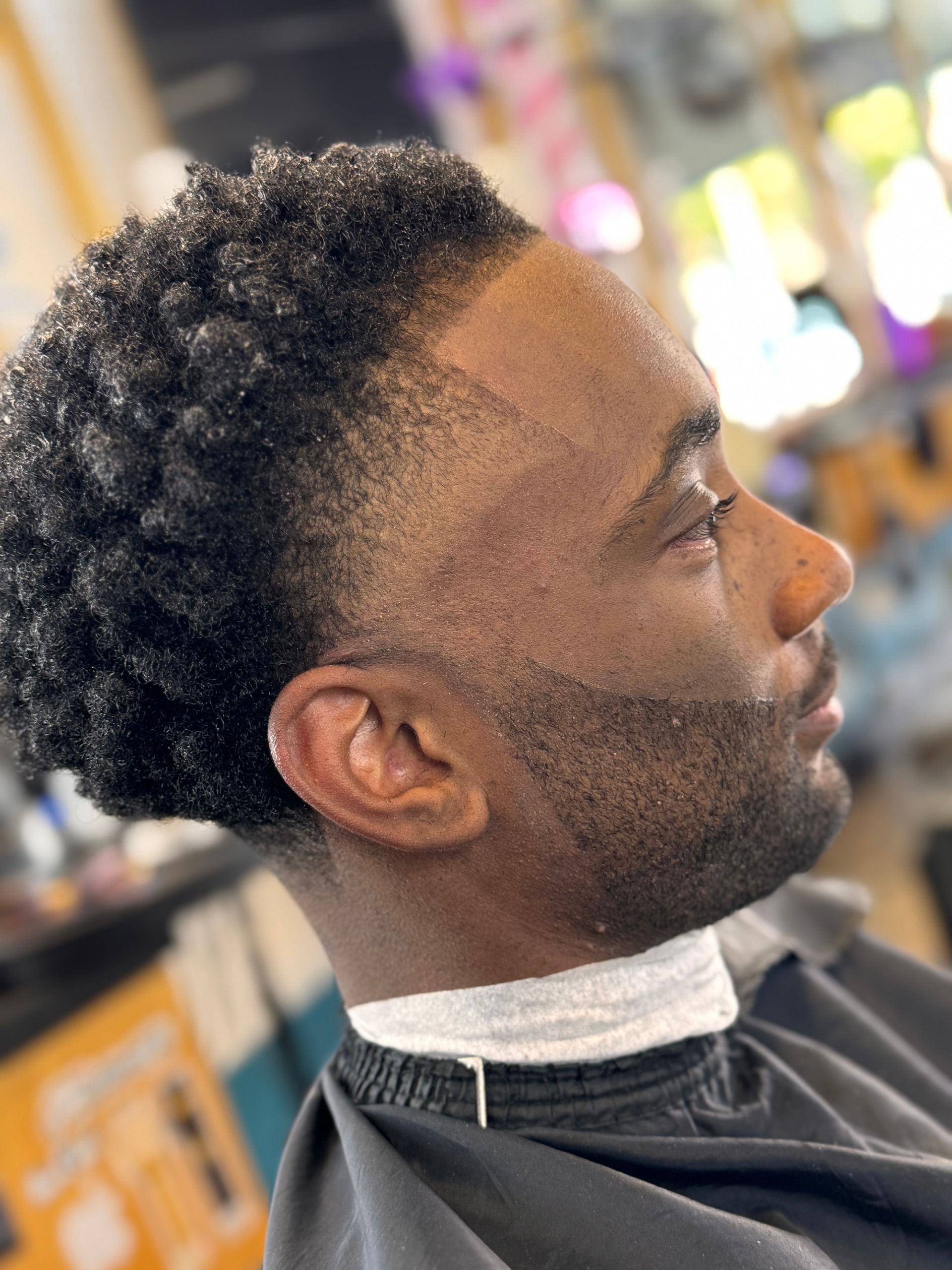 A man is getting his hair cut at a barber shop.