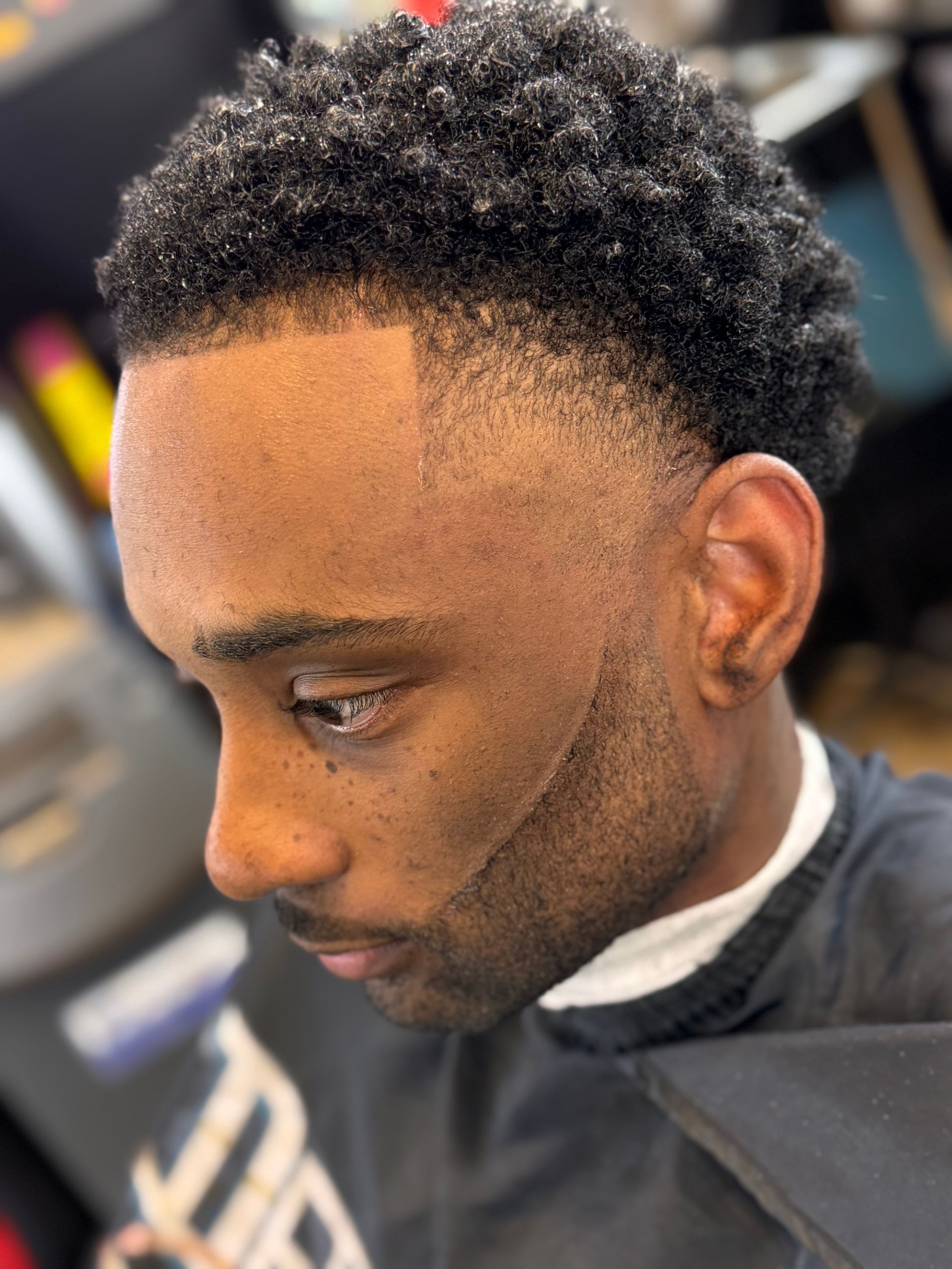 A man is getting his hair cut at a barber shop.