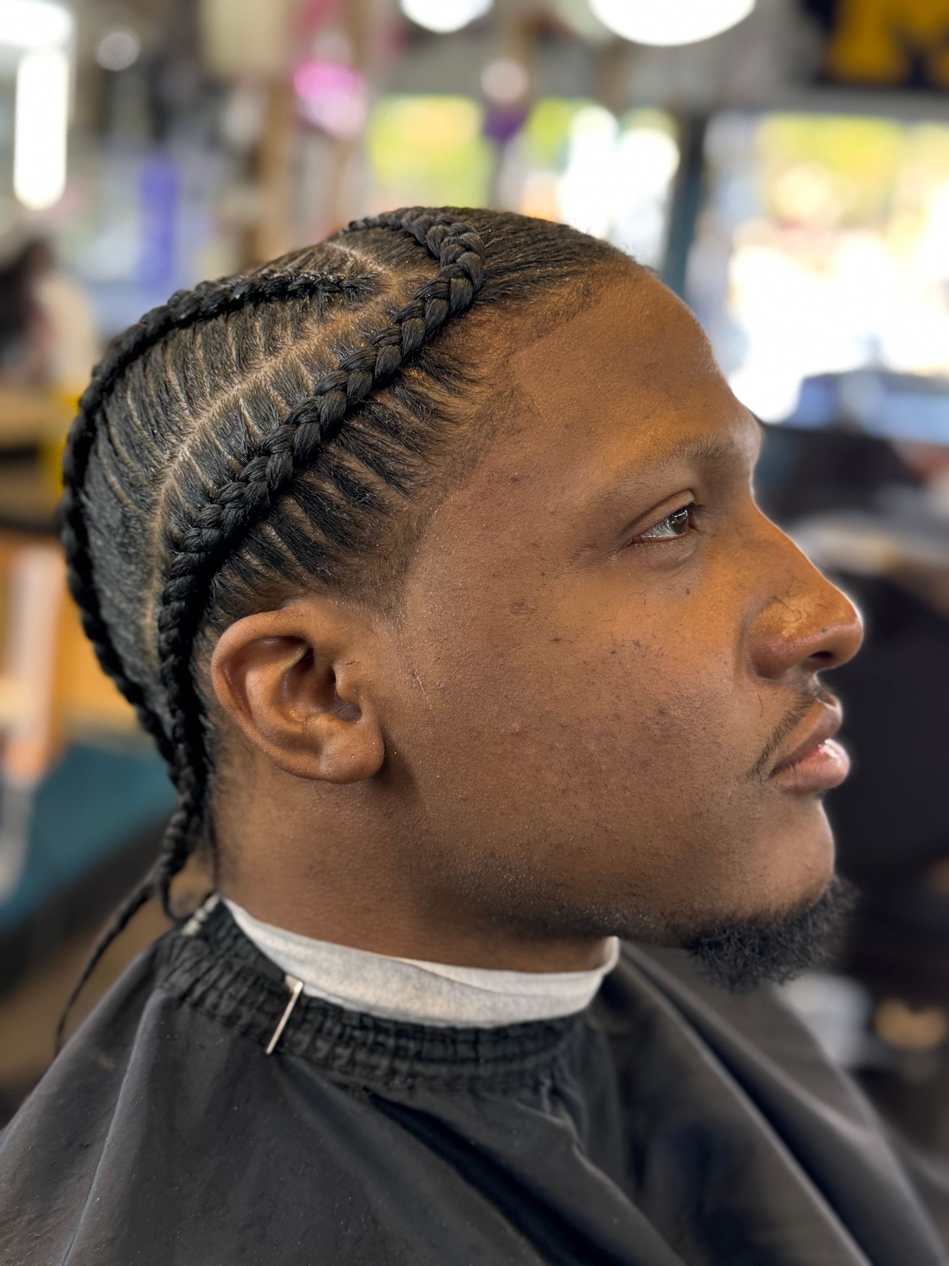 A man is getting his hair braided in a barber shop