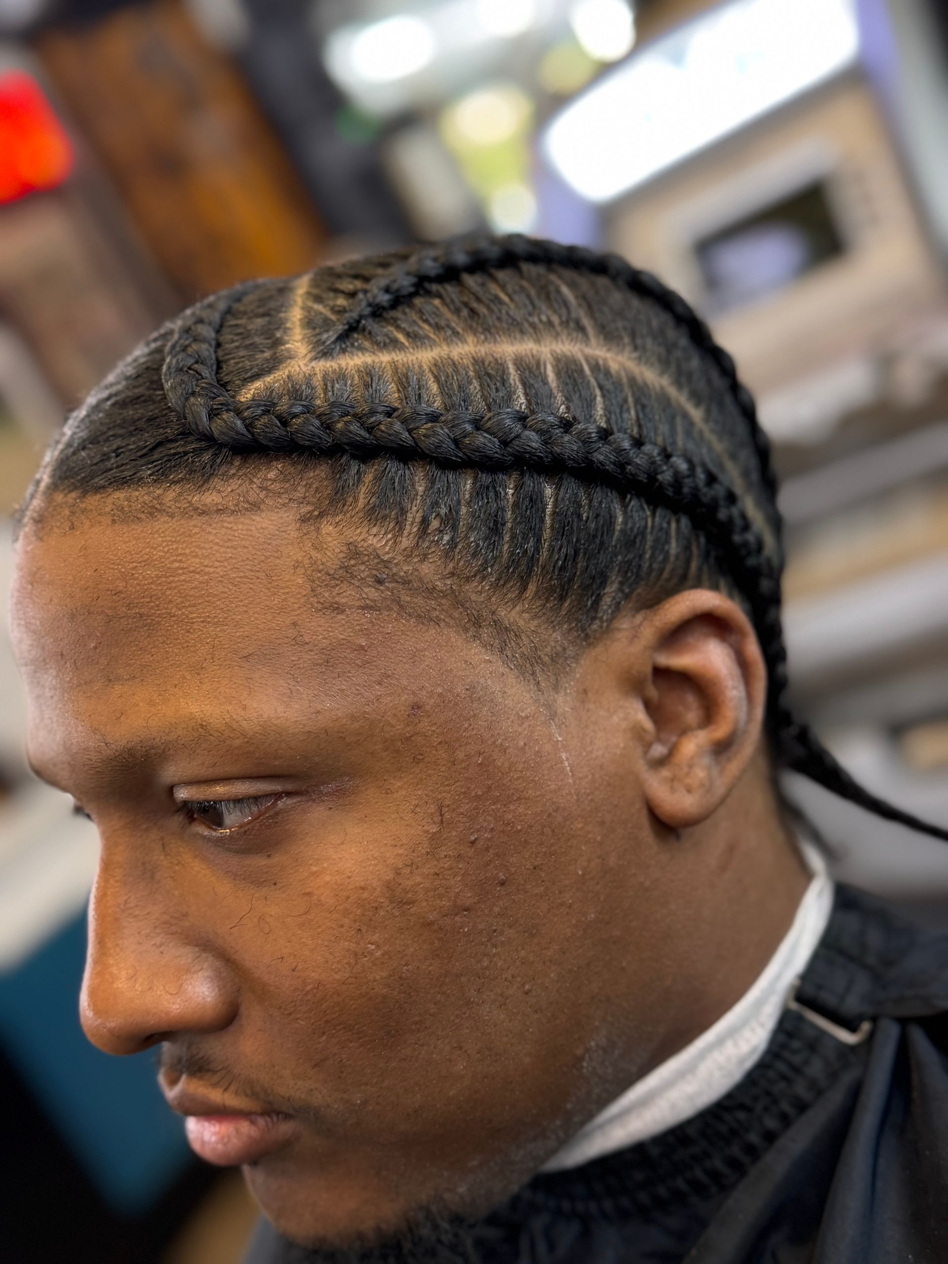 A man is getting his hair braided in a barber shop