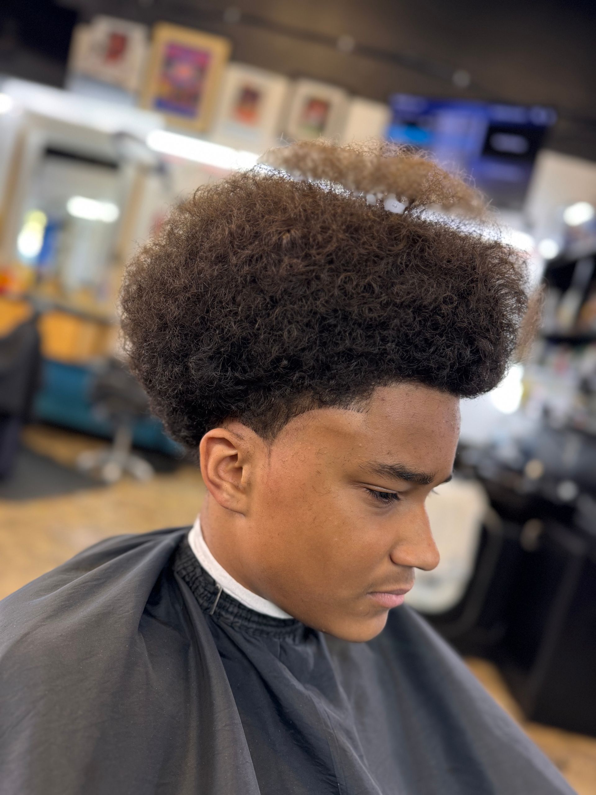 A young man is getting his hair cut at a barber shop.