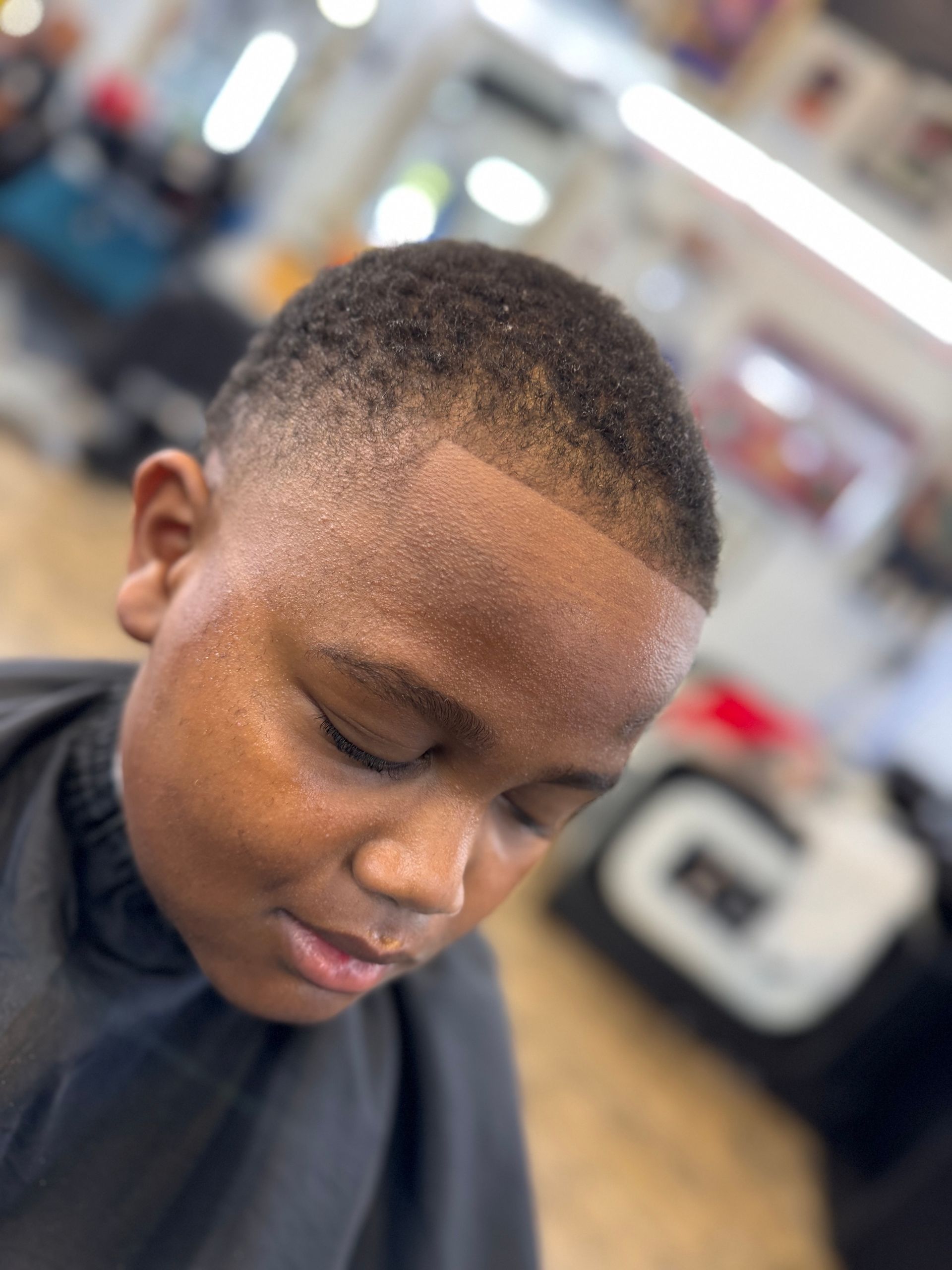 A young boy is getting his hair cut at a barber shop.