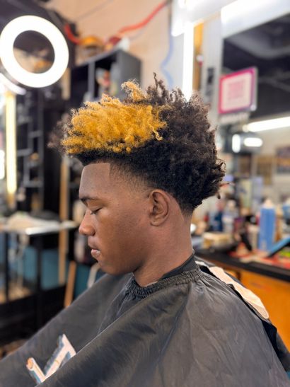 A man is getting his hair cut at a barber shop.