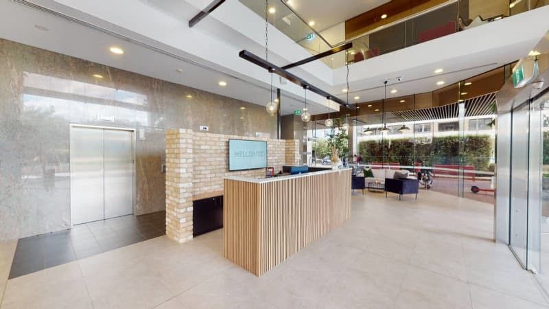 A large lobby with a wooden reception desk and an elevator.