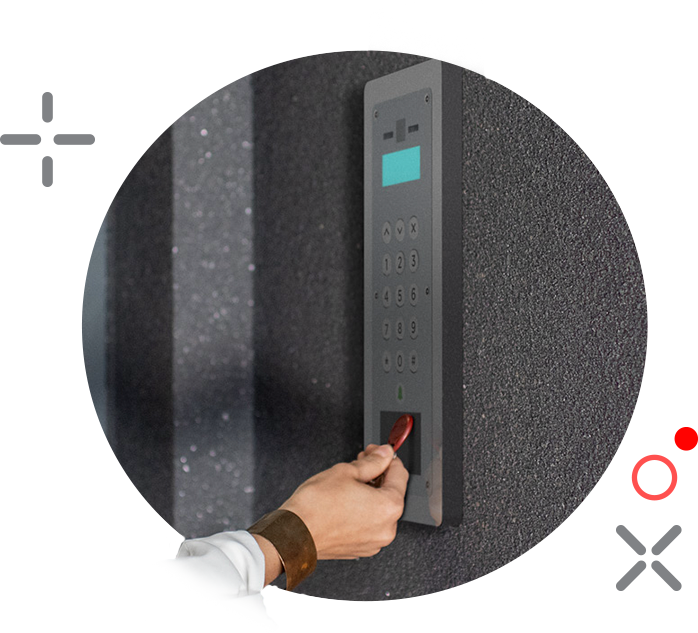 Person inserting a key card into a security system keypad on a dark, textured wall.