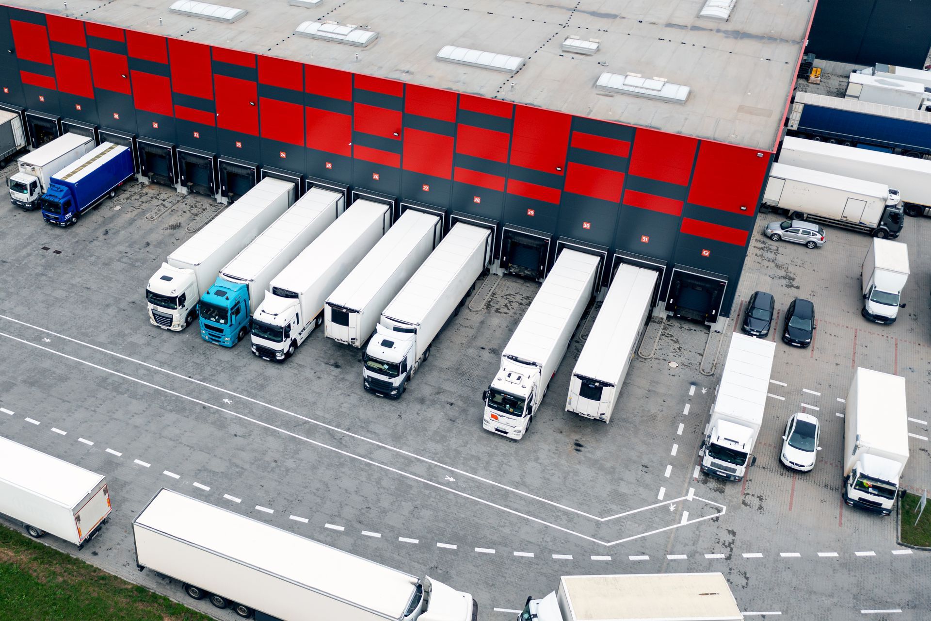 Trucks at a loading dock of a warehouse with red and gray exterior.