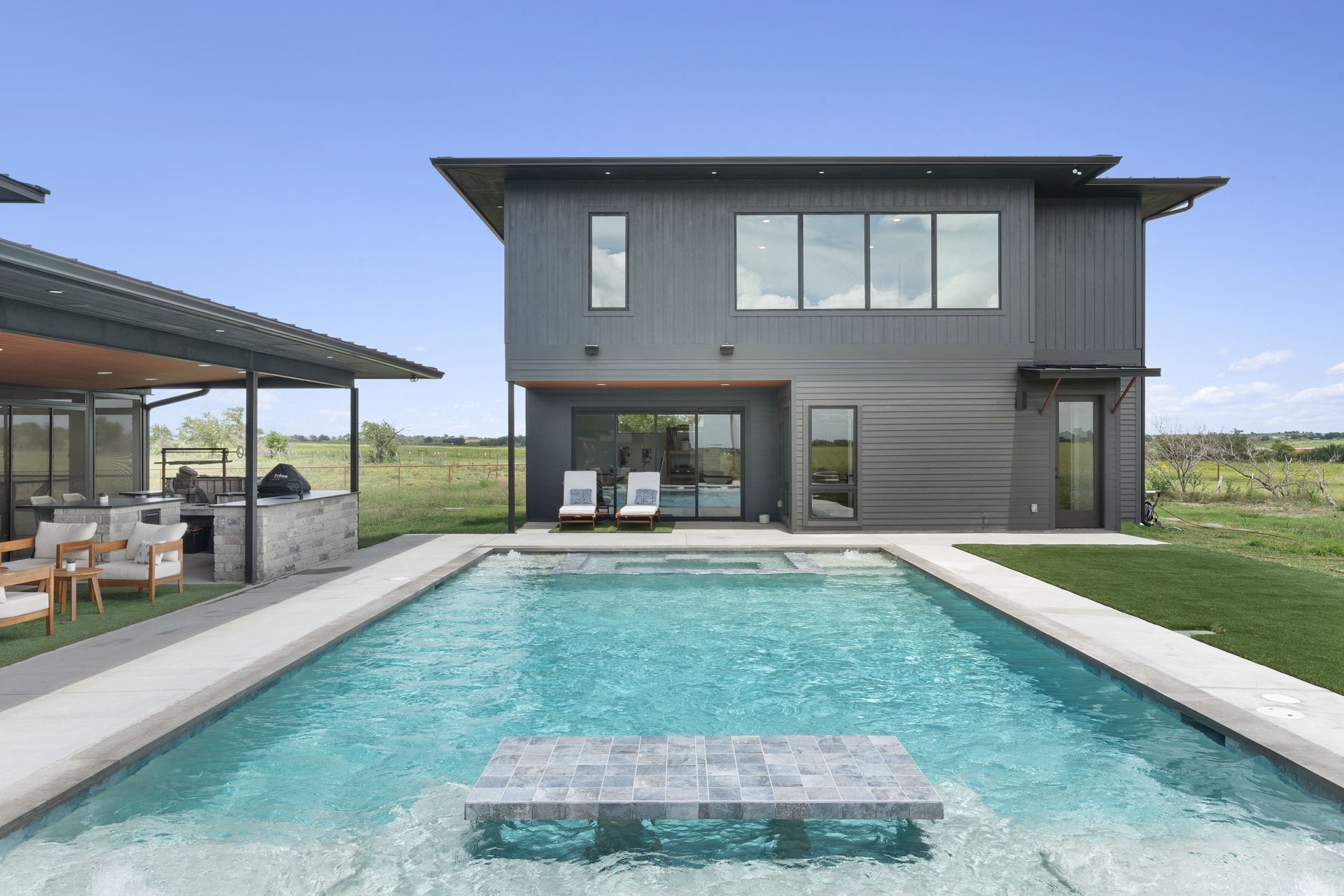 Modern house with a backyard swimming pool and covered patio under a clear sky