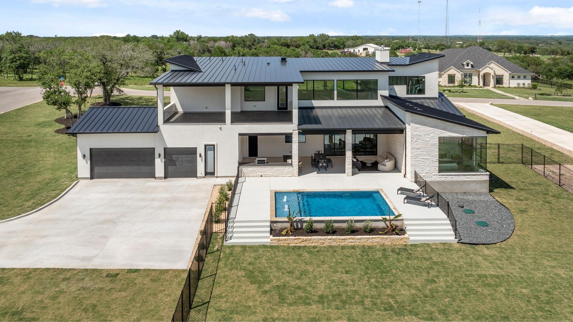 Modern two-story house with large pool, patio, and three-car garage on a grassy lot